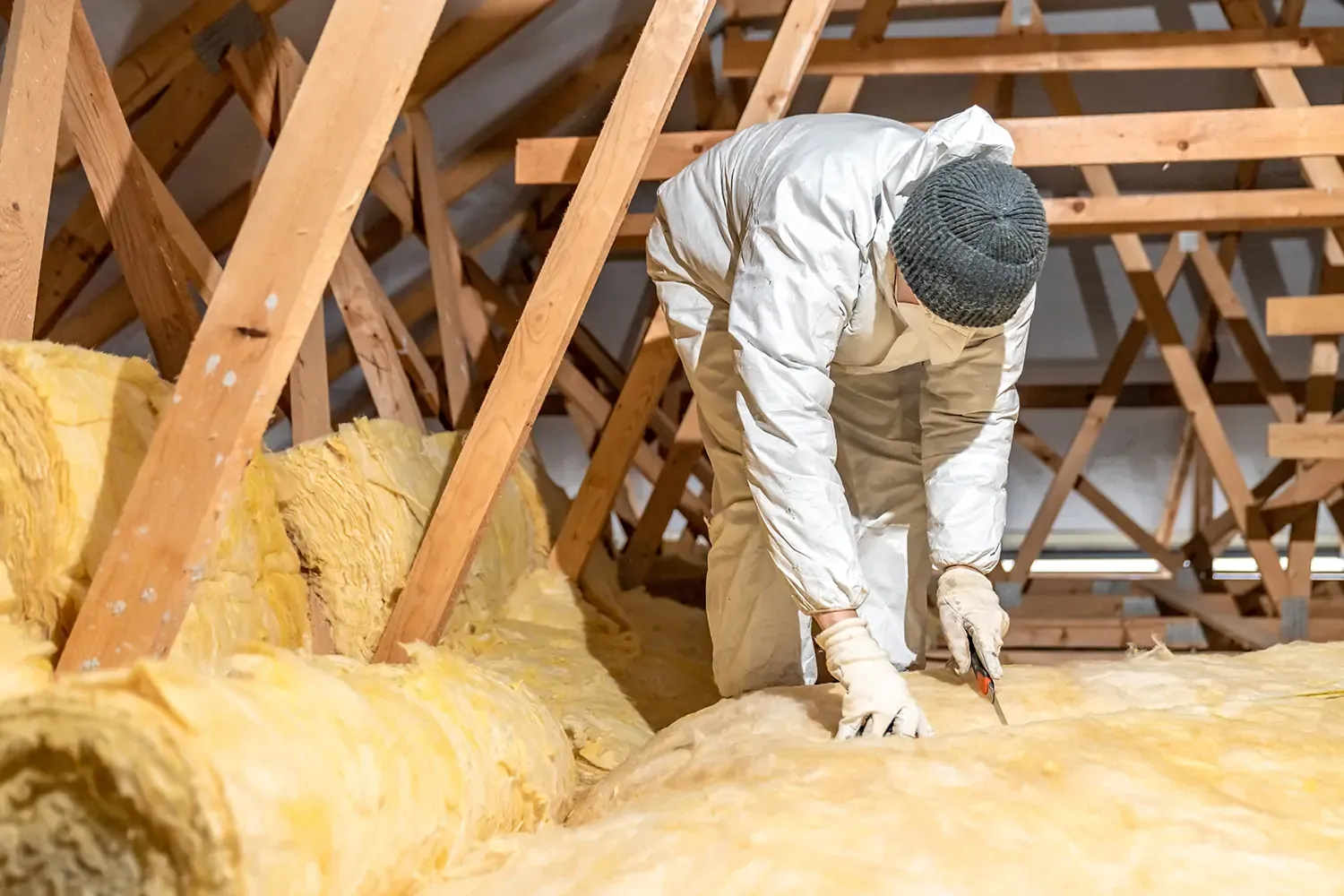 Man installing loft insulation as part of free loft insulation grants to improve home energy efficiency
