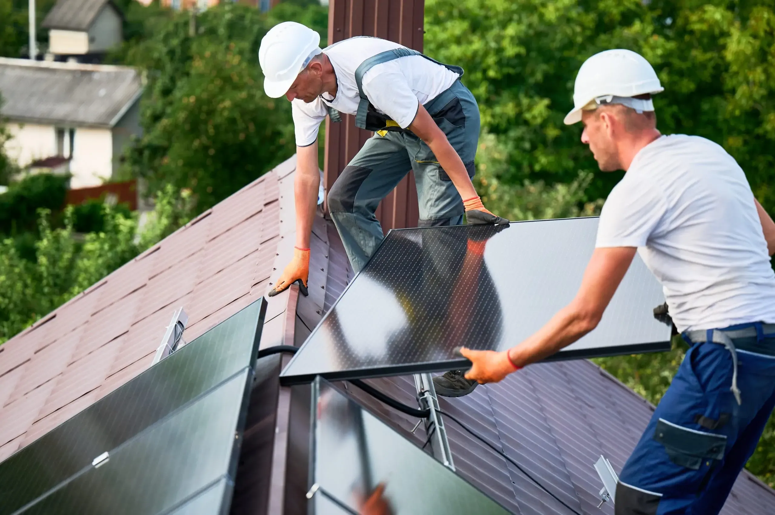 Two workmen installing solar panels as part of free government solar panel grants for energy-efficient home upgrades
