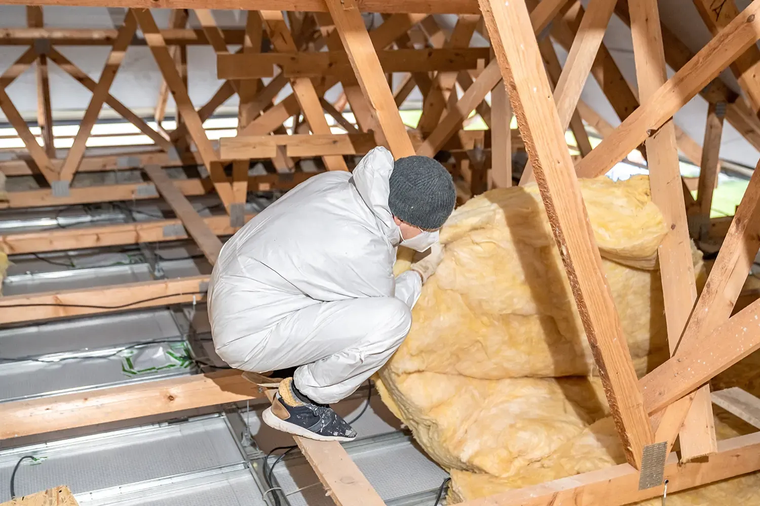 Man inspecting loft insulation installation to ensure proper fitting and energy efficiency in a home