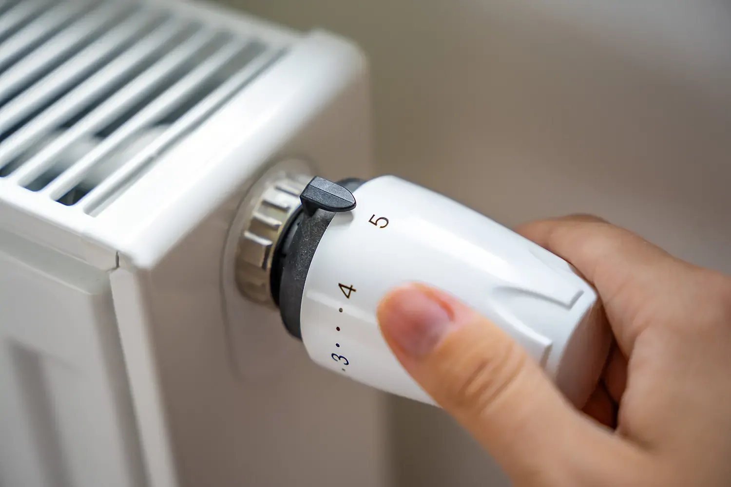 Person adjusting thermostat to control home heating temperature for energy efficiency and comfort