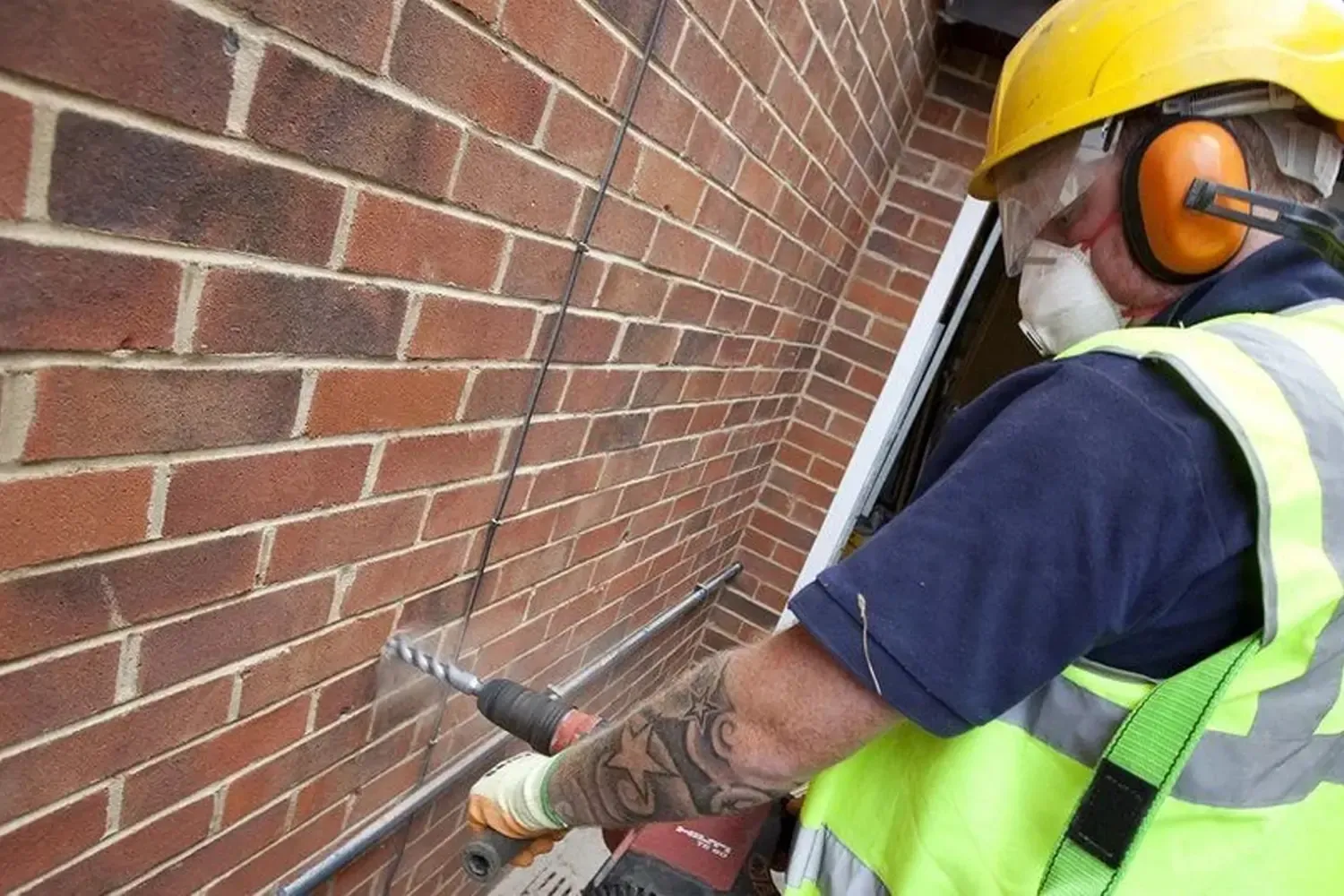Workman installing cavity wall insulation as part of a free government-funded home energy efficiency grant program