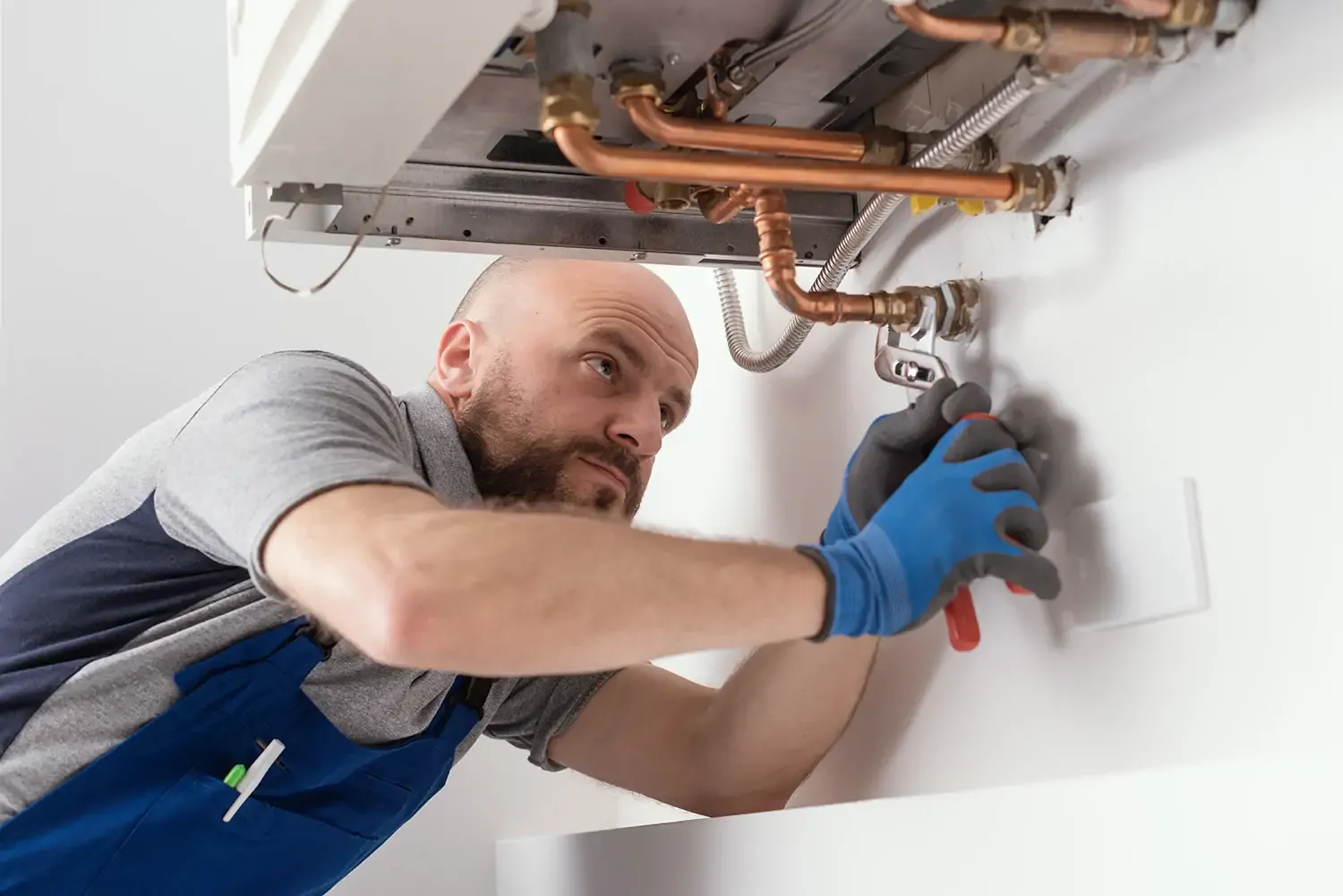 Professional gas engineer installing a natural gas boiler at home, he is checking the pipes