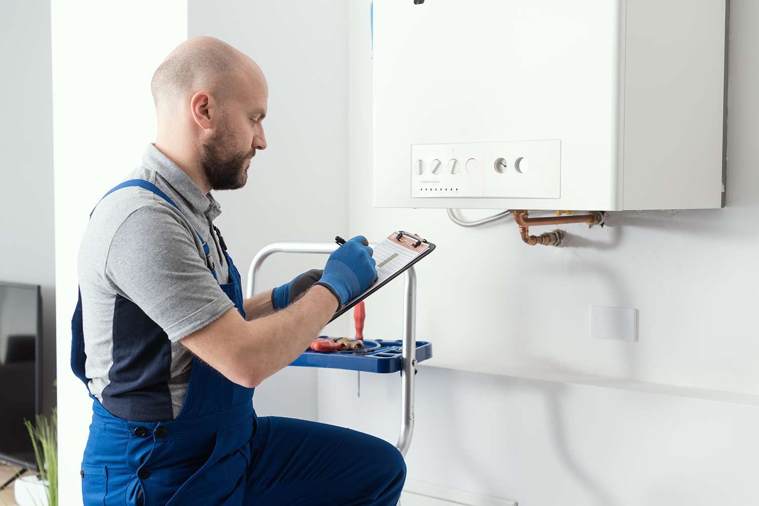 Gas engineer writing a gas safety certificate and boiler records after servicing